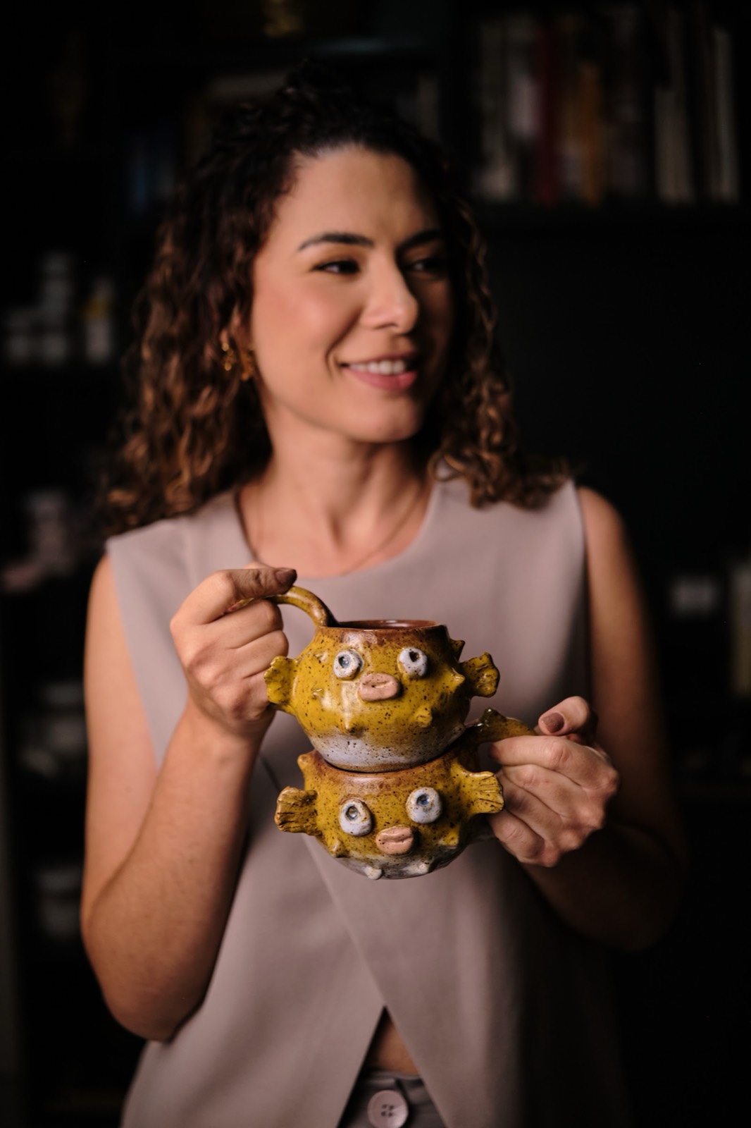Isabela segura as duas canecas baiacu